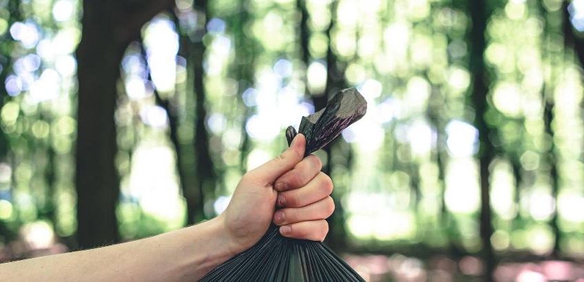 Close-up einer Hand, die eine Mülltüte hält – umweltbewusstes Verhalten beim Wandern und Naturschutz im Allgäu.