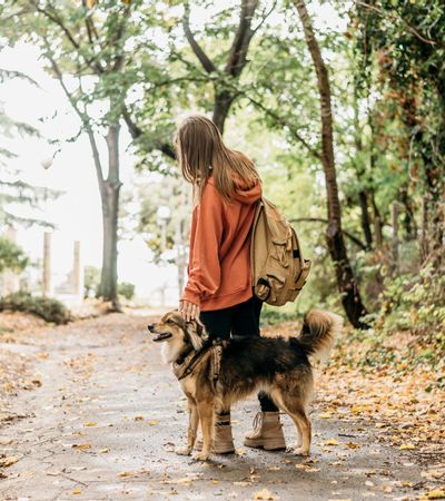 Junge Frau mit Rucksack und tierischem Begleiter auf einem herbstlichen Naturweg – Wanderung und Naturerlebnis im Allgäu.