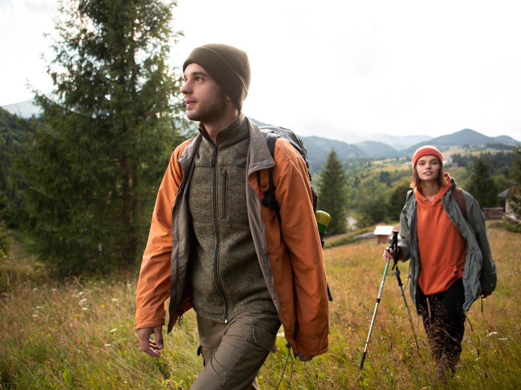 Junge Wanderer laufen im Herbst durch ein buntes Feld – herbstliche Naturerlebnisse und Aktivurlaub im Allgäu.