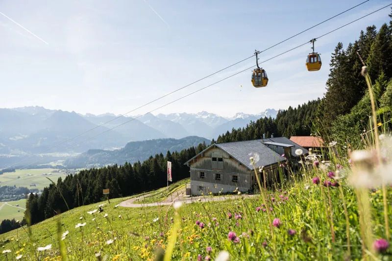 Gondeln schweben über einer Berghütte in den Allgäuer Alpen – malerische Berglandschaft und beliebtes Ausflugsziel.