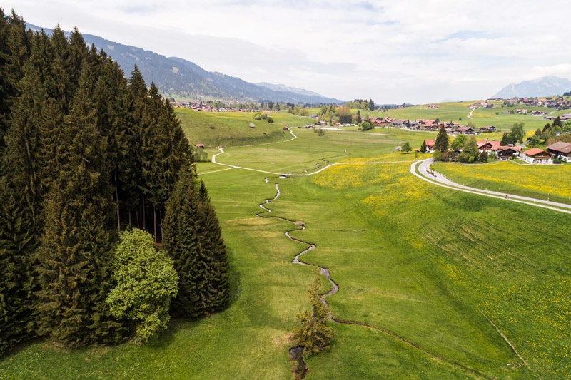 Idyllischer Riedbach bei Obermaiselstein im Allgäu – klare Bachlandschaft eingebettet in grüne Wiesen und Berge.
