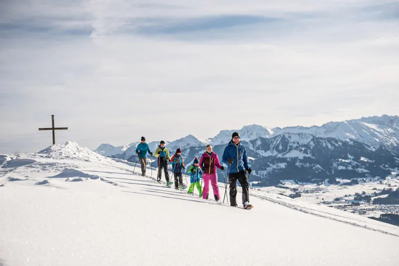Personen auf Schneeschuh-Tour in Ofterschwang, Allgäu – Winteraktivität in verschneiter Berglandschaft.