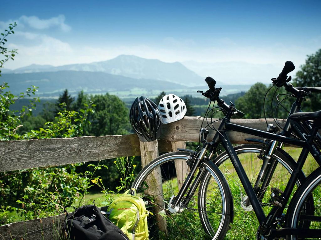 Radfahrer machen eine Pause mit Blick auf die beeindruckende Berglandschaft im Allgäu – aktiver Urlaub und Naturgenuss.
