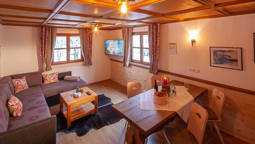 Gemütliches Wohnzimmer mit Holzoptik und warmem Licht, ausgestattet mit moderner Einrichtung – einladender Wohnbereich in einer Ferienwohnung im Allgäu.