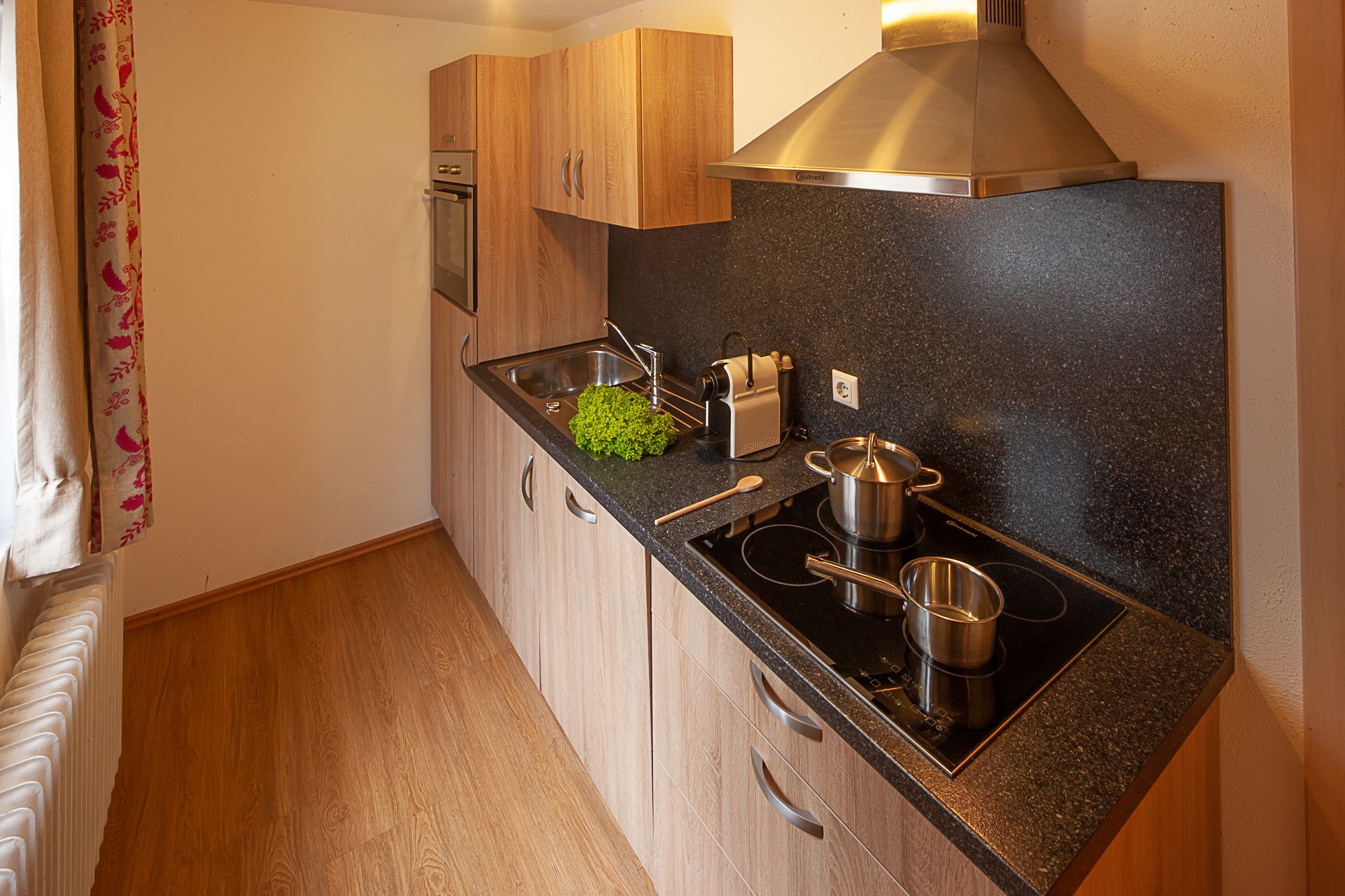 Moderne, voll ausgestattete Küche mit Holzoptik und allen wichtigen Geräten – ideal für Selbstversorger in einer Ferienwohnung im Allgäu.