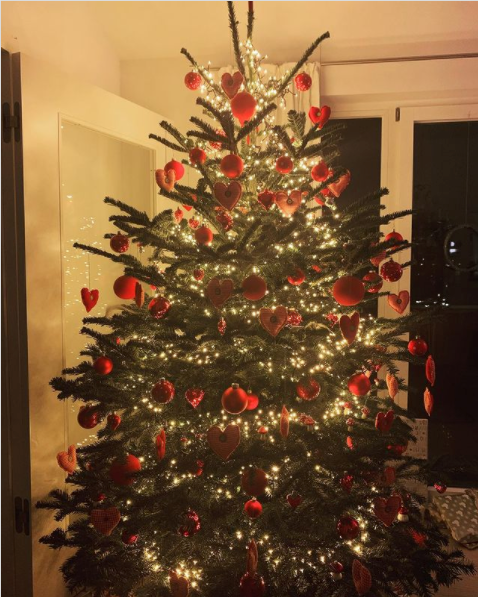 Ein rot geschmückter Weihnachtsbaum mit Lichterkette im dämmrigen Licht