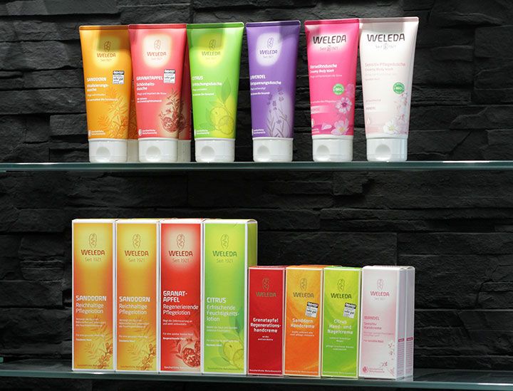 bunte Weleda Produkte auf einem Regal vor einer Schieferwand