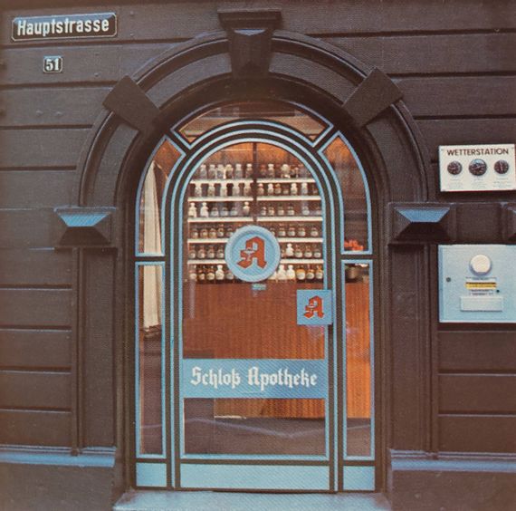 Eingangstüre in der Hauptstrasse mit Blick auf die Apothekengefäße im Inneren der Apotheke