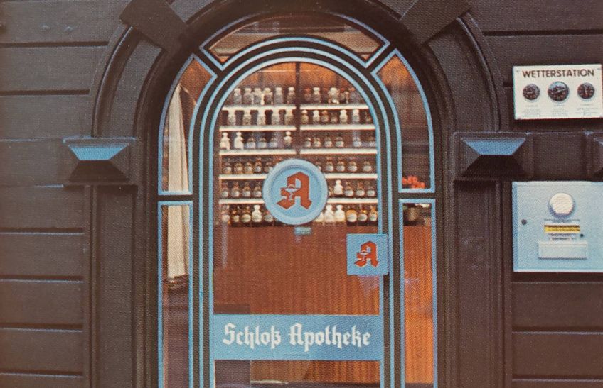 Eingangstüre in der Hauptstrasse mit Blick auf die Apothekengefäße im Inneren der Apotheke