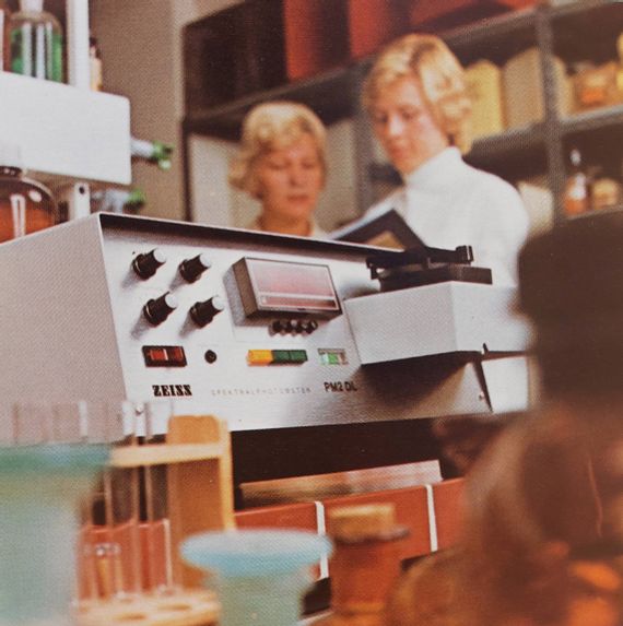 Laborgerät und Reagenzgläser, im Hintergrund 2 Laboranten