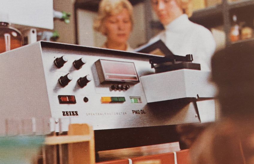 Laborgerät und Reagenzgläser, im Hintergrund 2 Laboranten