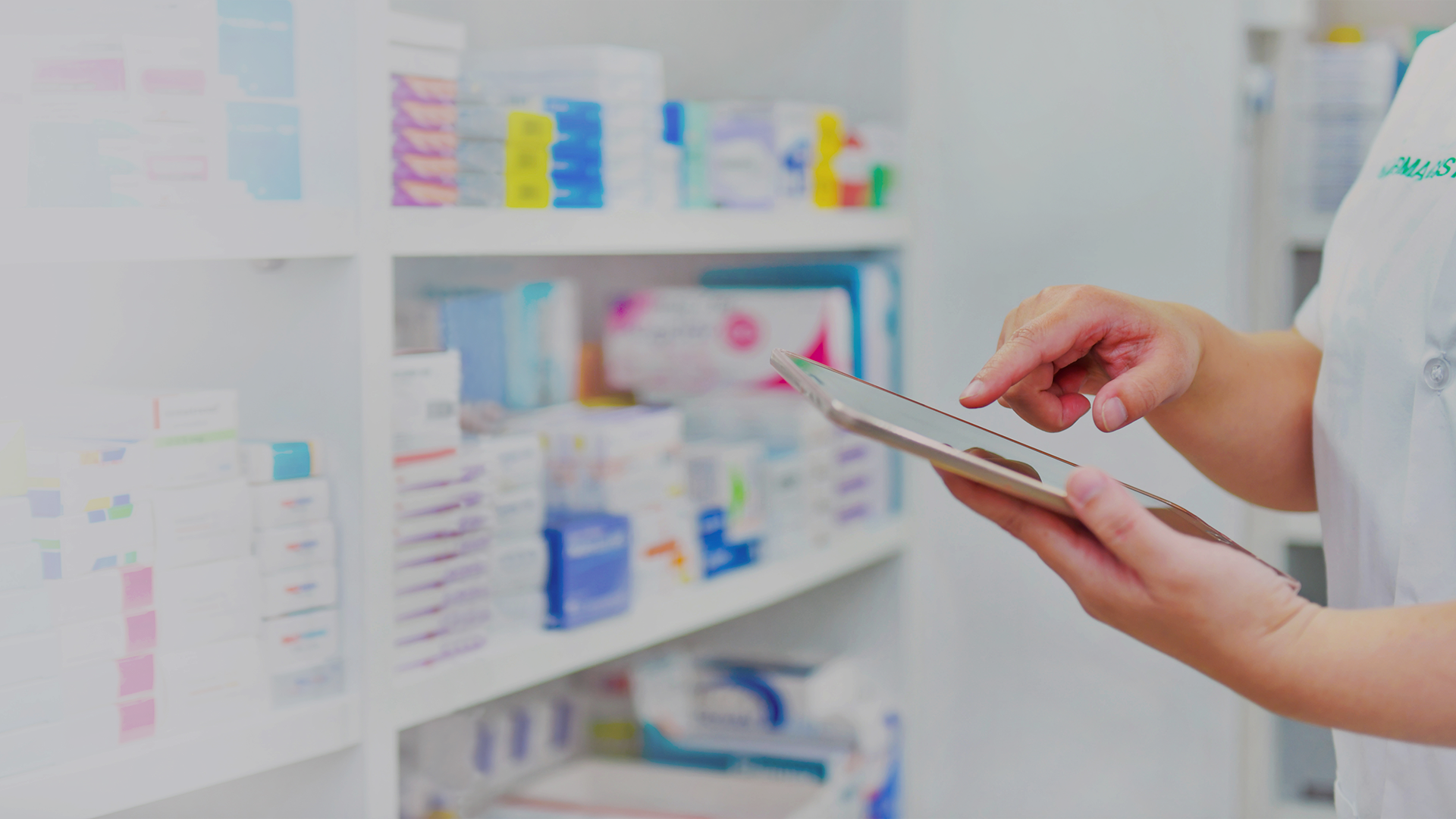 Eine Person mit einem Tablet in der Hand vor einem Arzneimittelregal