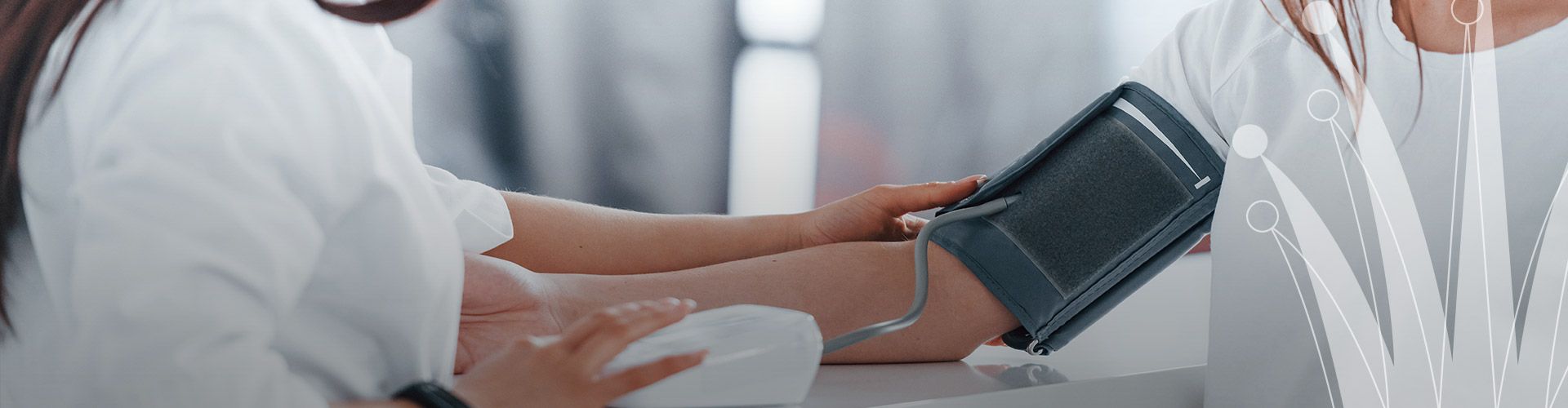eine Person misst der gegenübersitzenden Person mit einer Oberarmmanschette den Blutdruck