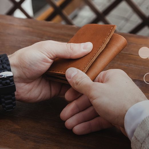 eine Person hält einen Ledergeldbeutel in den Händen