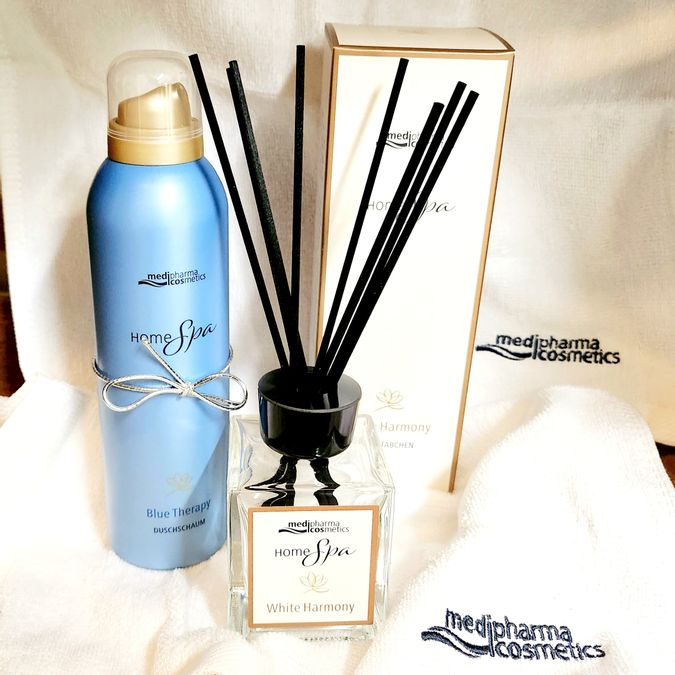 Duschschaum und Duftstäbchen in einem Glas auf Handtüchern aufgestellt