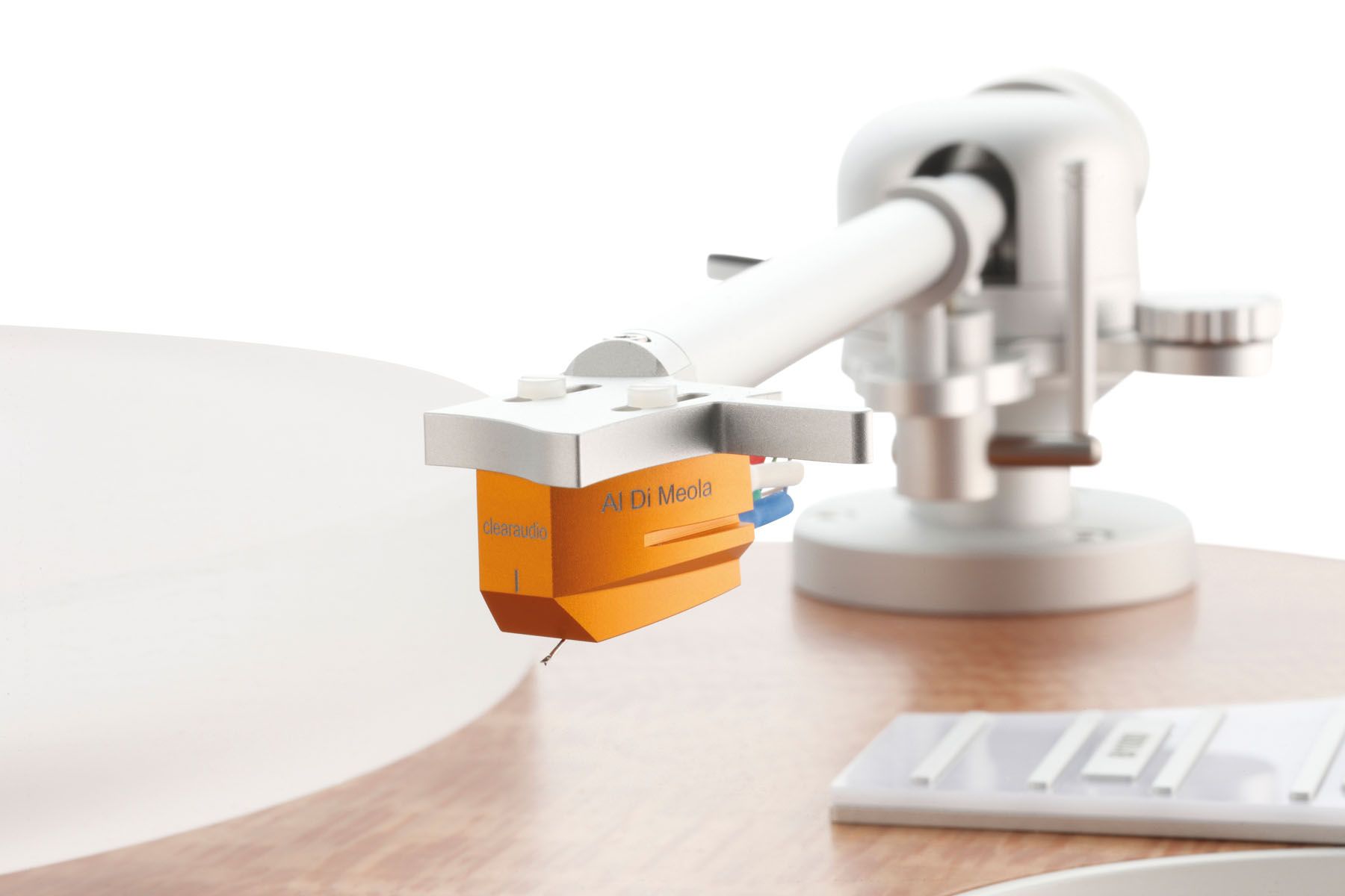 Fokus auf den eleganten weißen Clearaudio-Tonarm mit einem markanten, orangefarbenen Tonabnehmersystem.
