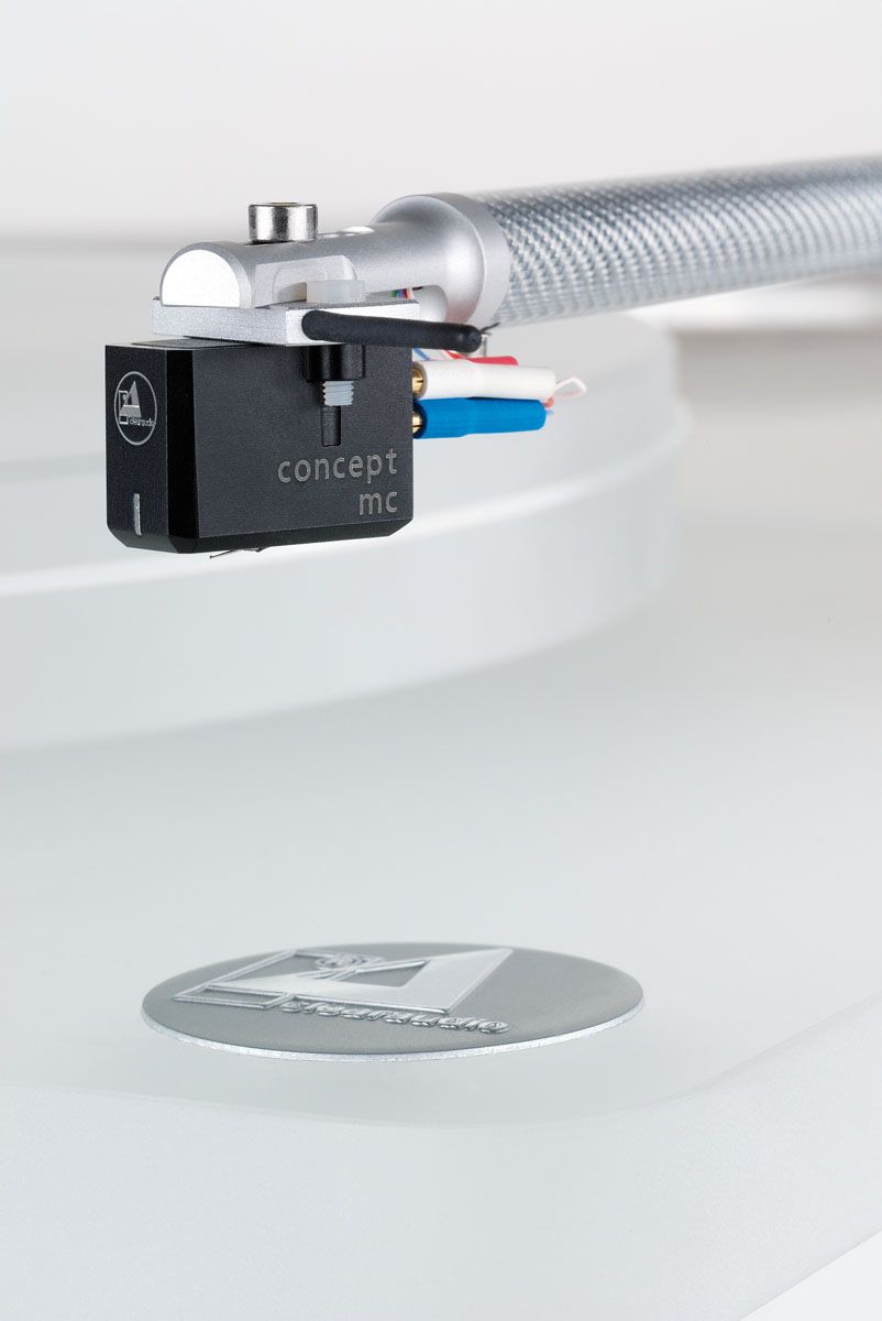 Nahaufnahme des Clearaudio Emotion SE Plattenspielers. Zu sehen ist ein präzise gefertigter Tonarm mit einem daran befestigten Clearaudio Concept V2 Tonabnehmer, der über einer matten, weißen Oberfläche schwebt. Das Gehäuse des Tonabnehmers ist schwarz mit dem markanten Clearaudio-Schriftzug.
