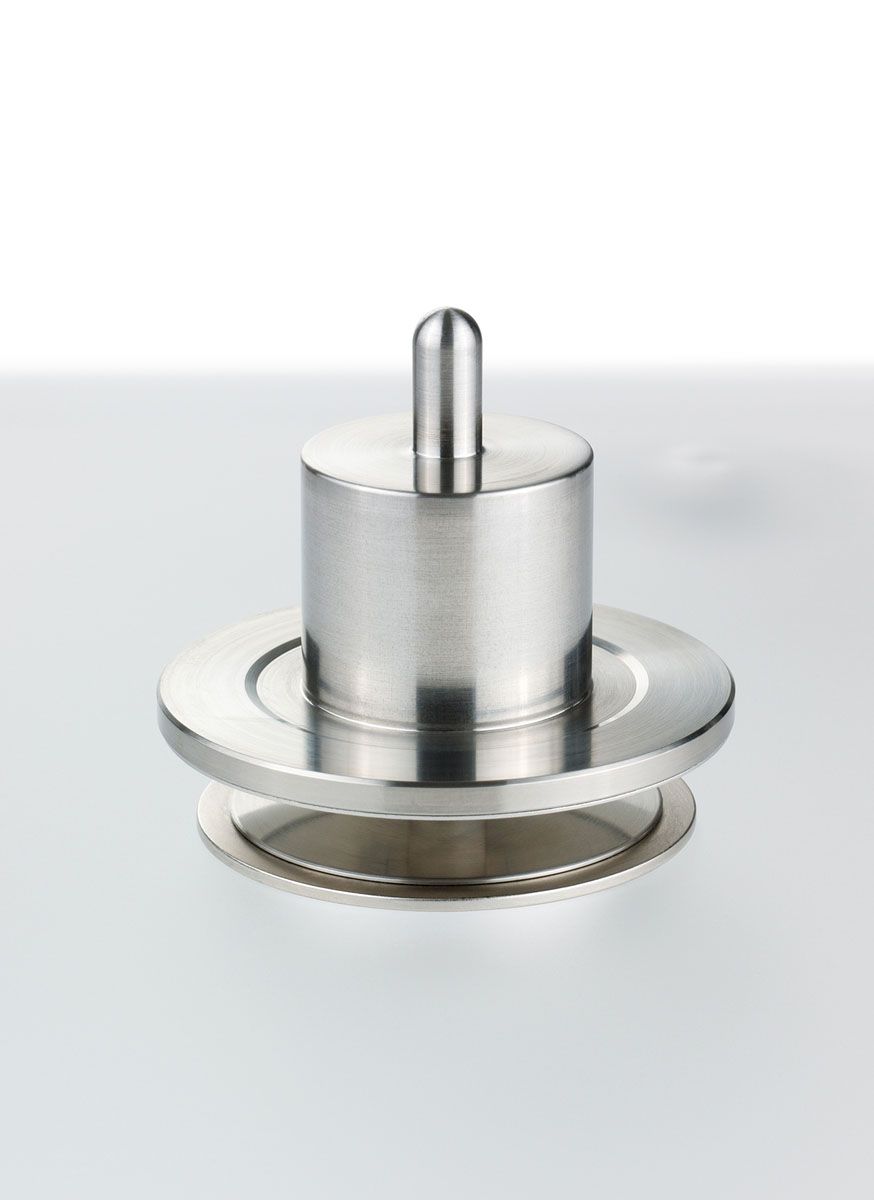 Eine isolierte Studioaufnahme des magnetlagerfreien Clearaudio CMB-Plattentellerlagers. Es zeigt eine präzise gedrehte Metallwelle auf einer runden Metallbasis, die für eine reibungsfreie Rotation sorgt. Der Hintergrund ist ein sauberer, weißer Raum.