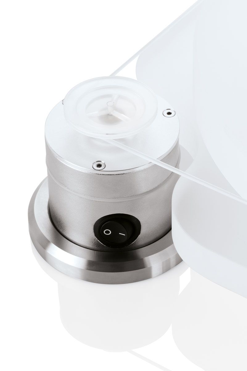 Eine Detailansicht der Unterseite des separaten Motorgehäuses für den Clearaudio Emotion SE. Zu sehen ist der schwarze Wippschalter für die Stromversorgung, umgeben von einem präzise gefertigten Aluminiumgehäuse. Der Flachriemenantrieb, der den Teller verbindet, ist ebenfalls teilweise sichtbar.