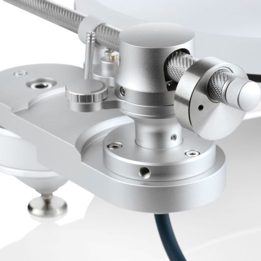 Nahaufnahme der silbernen, präzise gefrästen Tonarmbasis und des Lagers eines Clearaudio Drehtonarms auf dem hellen Innovation Basic Chassis.