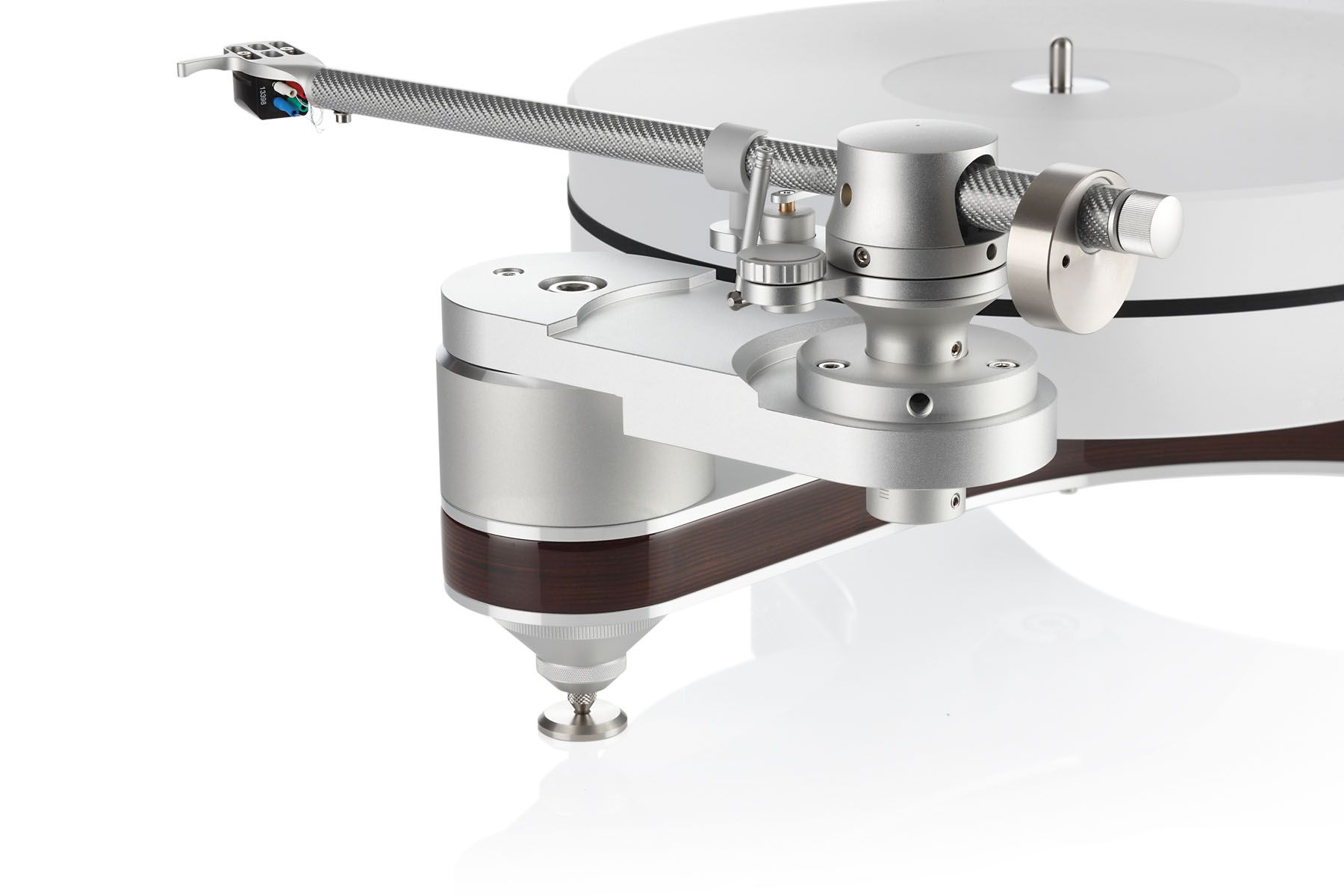 Nahaufnahme eines silbernen clearaudio Innovation Compact Laufwerks, fokussiert auf die massive Tonarmbasis und das Tonarmlager vor weißem Hintergrund. Die Schichtung aus silbernem Aluminium und dem dunkelbraunen Panzerholz-Kern des Chassis ist an der Flanke gut erkennbar. Das System ruht auf einem höhenverstellbaren, spitz zulaufenden Metallfuß.