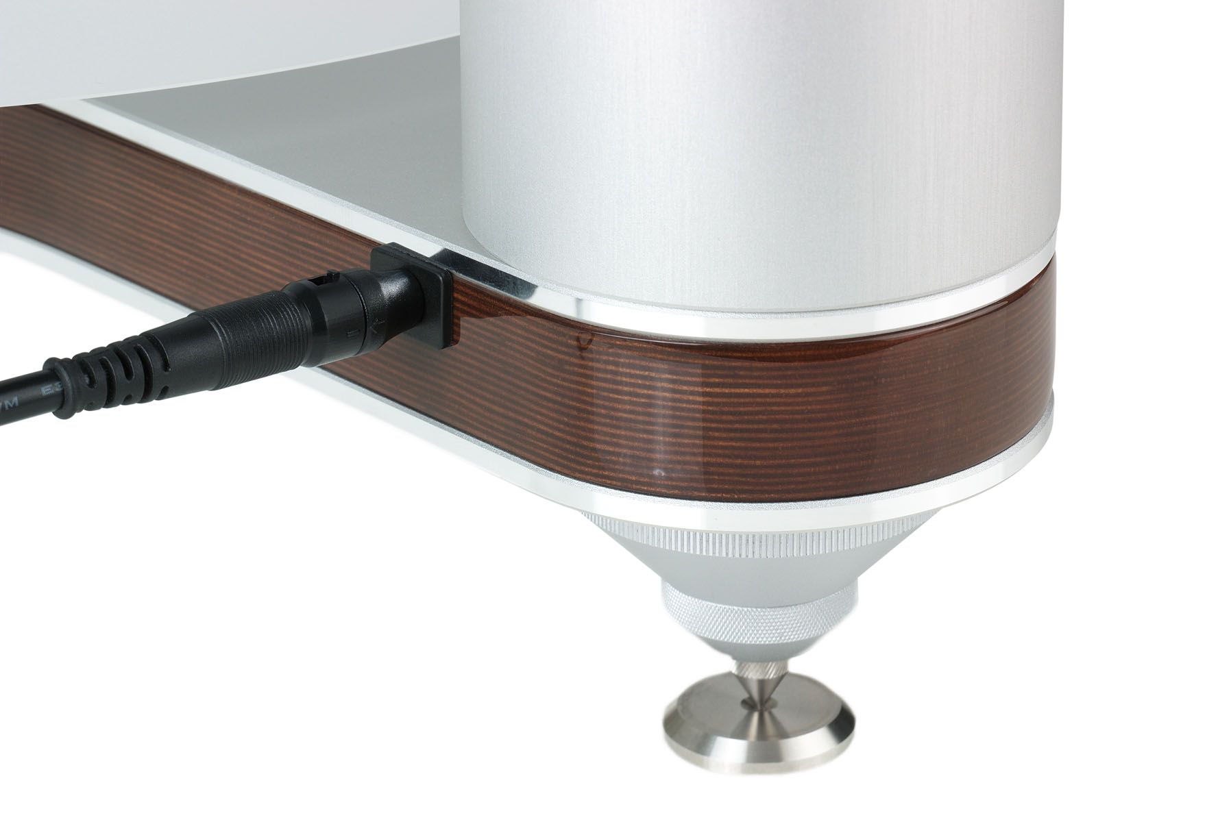Extreme Nahaufnahme des Gehäuserands und eines Gerätefußes des clearaudio Innovation Compact Wood. Man sieht die feine, mehrschichtige Struktur des braunen Panzerholzes, das von silbernem Aluminium umschlossen wird. Ein schwarzes Stromkabel ist in die Rückseite eingesteckt. Das Gerät steht auf einem silbernen, kegelförmigen Fuß mit Unterlegscheibe.