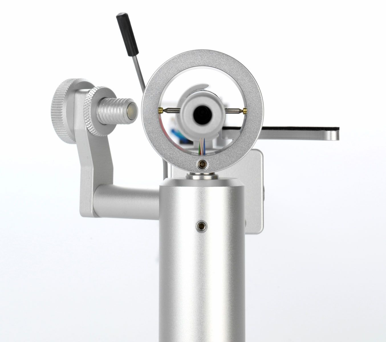 Technische Nahaufnahme der kardanischen Lagerung des silbernen clearaudio Satisfy Kardan Tonarms von hinten vor weißem Hintergrund. Im Zentrum ist der kreisrunde Lagerring zu sehen, in dem das Tonarmrohr horizontal und vertikal nadelgelagert ist. Links daneben befindet sich die filigrane Mechanik für das magnetische Anti-Skating mit einer gerändelten Justierschraube. Im Inneren des Rings sind unten die feinen, farbigen Tonarmkabel (rot, grün, blau) zu erkennen.