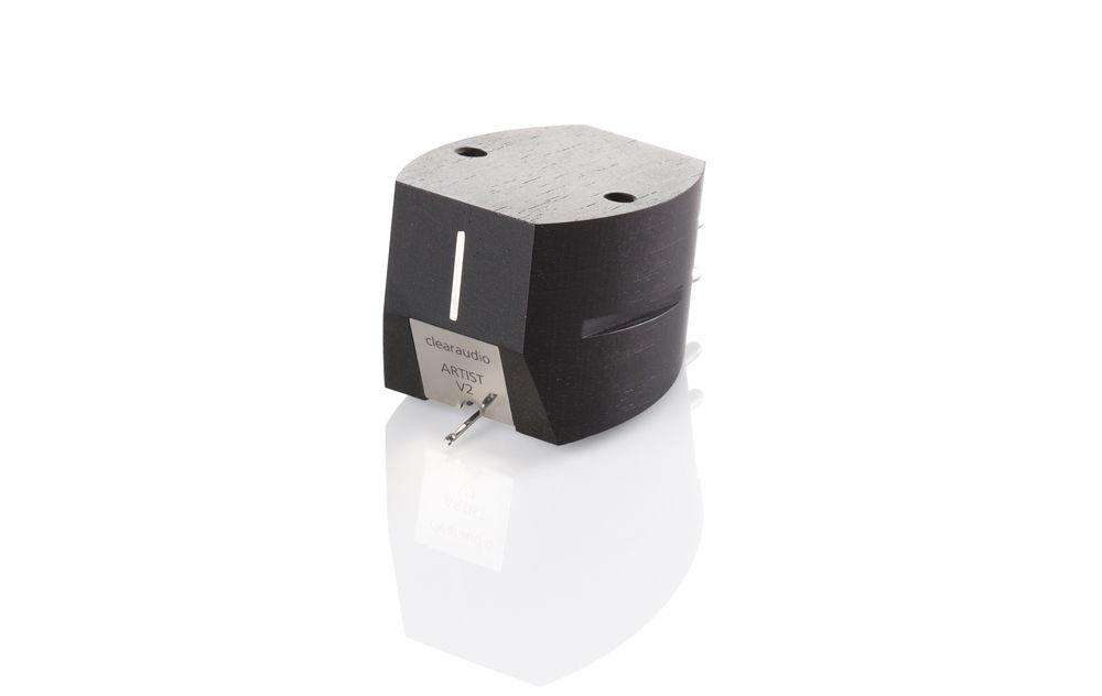 Produktfoto des clearaudio „Artist V2“ Tonabnehmers für Plattenspieler vor rein weißem Hintergrund. Das mattschwarze Gehäuse aus Ebenholz zeigt eine feine Holzmaserung und spiegelt sich leicht auf der weißen Oberfläche nach unten. An der Vorderseite befindet sich ein silbernes Plättchen mit dem Marken- und Modellnamen sowie der nach unten ragende Nadelträger.