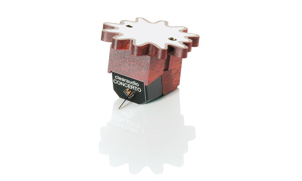 Produktfoto des clearaudio „Concerto V2“ Moving-Coil-Tonabnehmers vor weißem Hintergrund. Das Gehäuse besteht aus rötlich-braunem Schlangenholz, dessen Oberseite in eine charakteristische, stern- oder zahnradförmige Zwölfeck-Form (Flower-Design) ausläuft. An der schwarzen Front ist der weiße Schriftzug „clearaudio CONCERTO“ aufgedruckt, darunter ragt der feine Nadelträger heraus. Das gesamte System spiegelt sich deutlich nach unten ab.