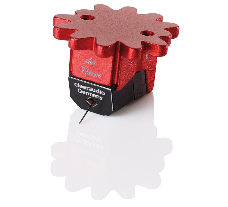 Studioaufnahme des freigestellten Clearaudio da Vinci V2 MC-Tonabnehmers mit metallisch-rot beschichtetem Aluminiumkörper und zahnradförmiger Oberseite auf weißem, spiegelndem Grund.