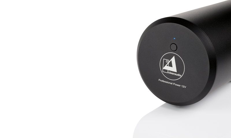 Nahaufnahme der runden Frontseite des zylindrischen, schwarzen clearaudio Professional Power 12V Netzteils mit Markenlogo und kleiner blauer LED auf weißem Grund.