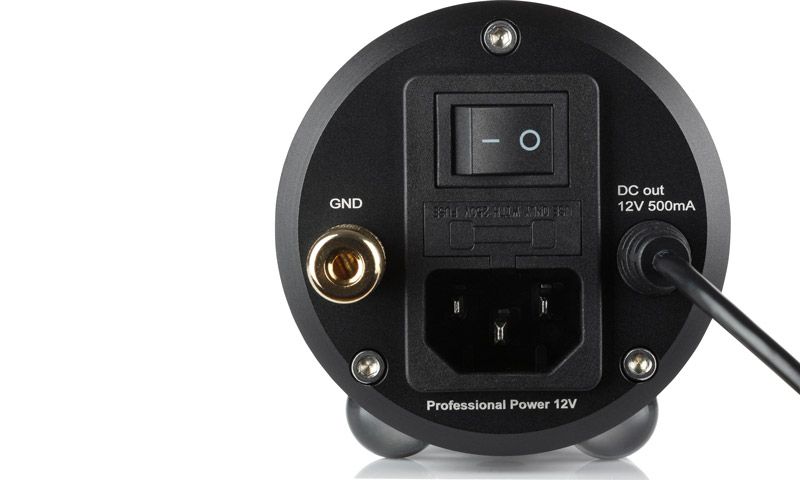 Rückansicht des runden clearaudio Professional Power 12V Netzteils mit Netzschalter, Kaltgeräte-Stromanschluss, goldener Erdungsklemme (GND) und DC-Ausgangskabel.
