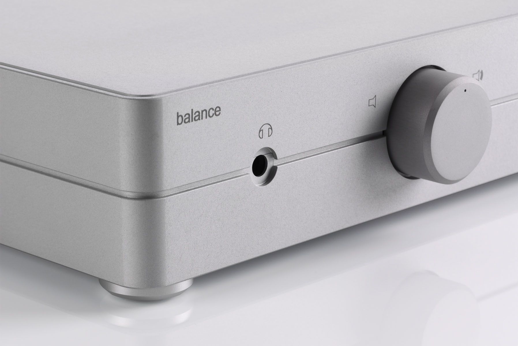 Nahaufnahme der silbernen Frontplatte des clearaudio balance Audiogeräts mit dem eingravierten Schriftzug „balance“, einer Klinkenbuchse für Kopfhörer samt Symbol und einem großen Lautstärkedrehregler auf weißem Hintergrund.
