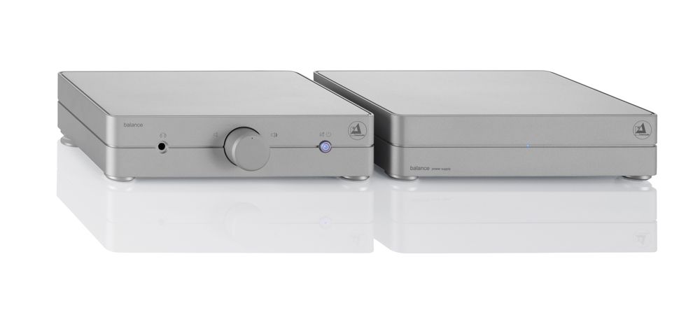 Zwei silberne, flache Gehäusekomponenten der clearaudio balance V2 Phonovorstufe und des passenden externen Netzteils nebeneinander auf weißem, spiegelndem Untergrund.