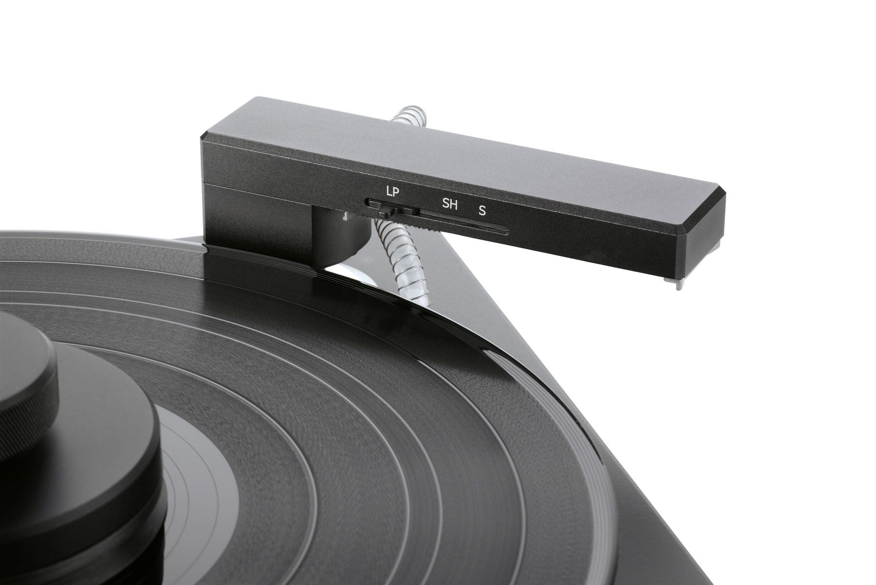 Nahaufnahme eines schwarzen Reinigungsarms über einer Vinyl-Schallplatte mit kleinen Beschriftungen zur Größenanpassung vor weißem Hintergrund.