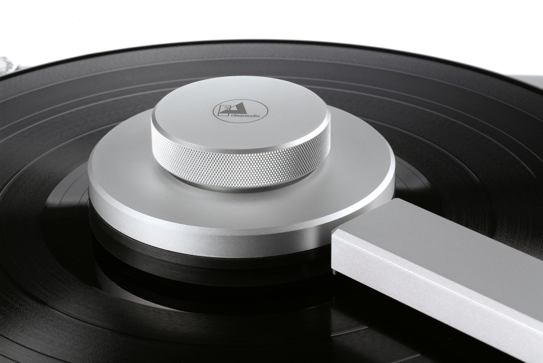 Nahaufnahme einer runden, silbernen Plattenklemme mit geriffeltem Rand und eingraviertem clearaudio Logo im Zentrum einer schwarzen Vinyl-Schallplatte.