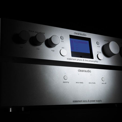 Zweiteiliges, silbernes clearaudio statement phono Audiosystem bestehend aus Vorverstärker und Akku-Netzteil, dramatisch inszeniert vor schwarzem Hintergrund.
