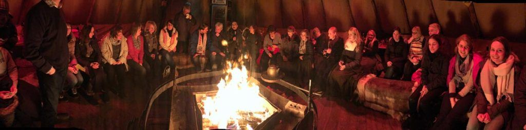 Teamevent - Weihnachtsfeier Mitarbeiter sitzen am offenen Feuer