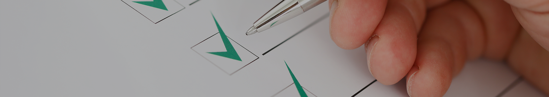 Hand hält Kugelschreiber und macht Haken