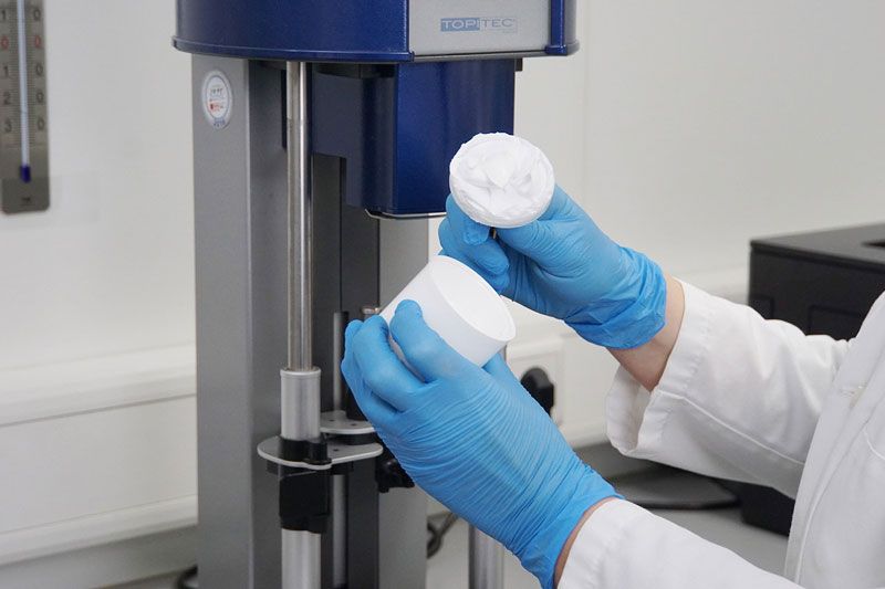 Hände halten eine geöffnete Kruke vor dem Topitec