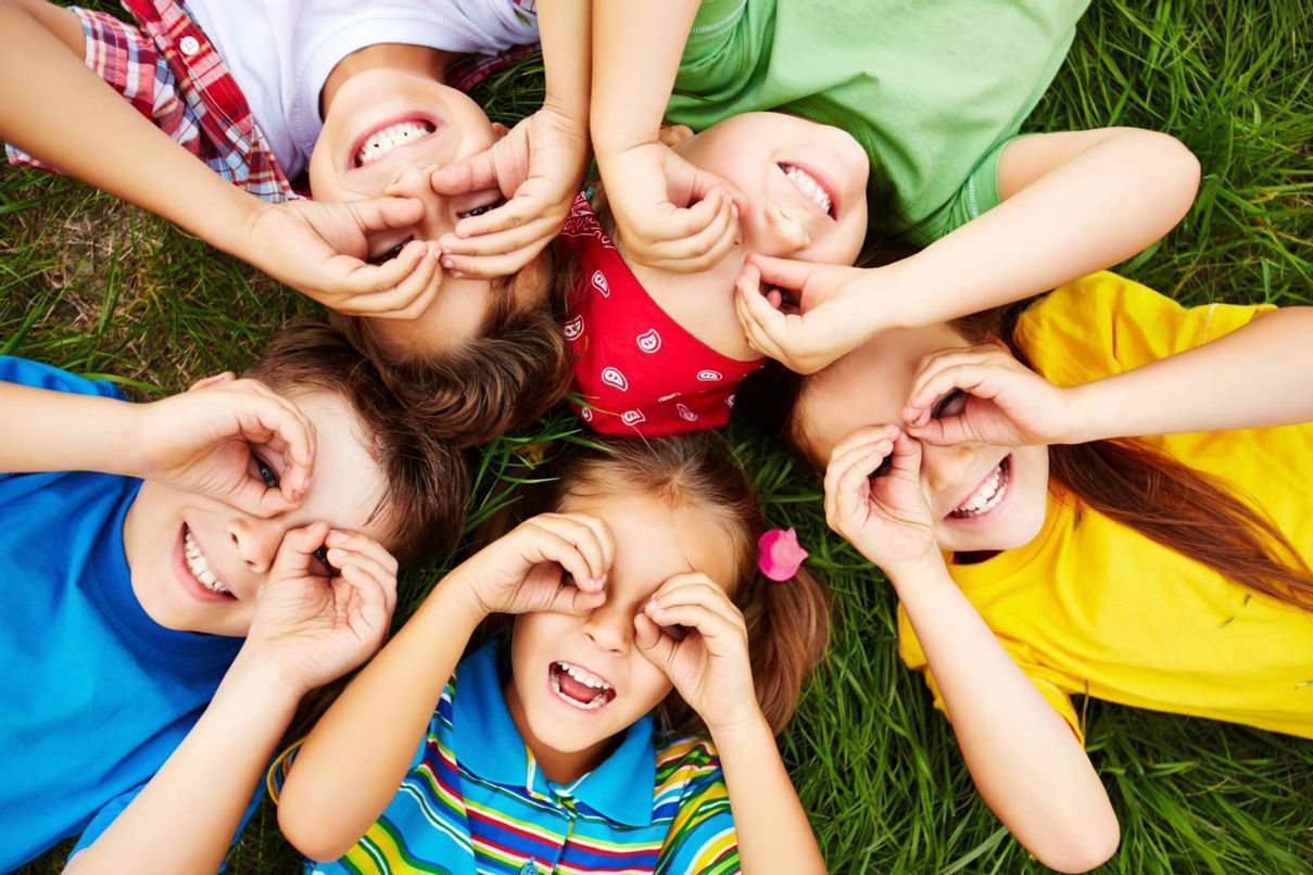 glückliche Kinder liegen im Kreis auf einem Rasen