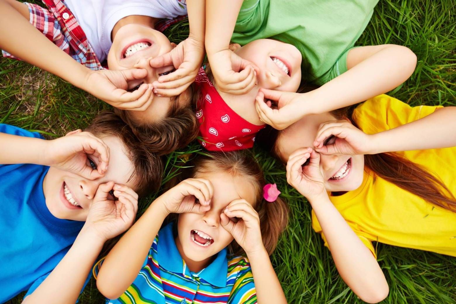 glückliche Kinder liegen im Kreis auf einem Rasen