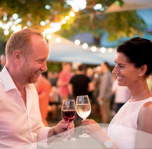 Ein Mann und eine Frau stoßen mit Weingläsern an beim Fest Komm und See