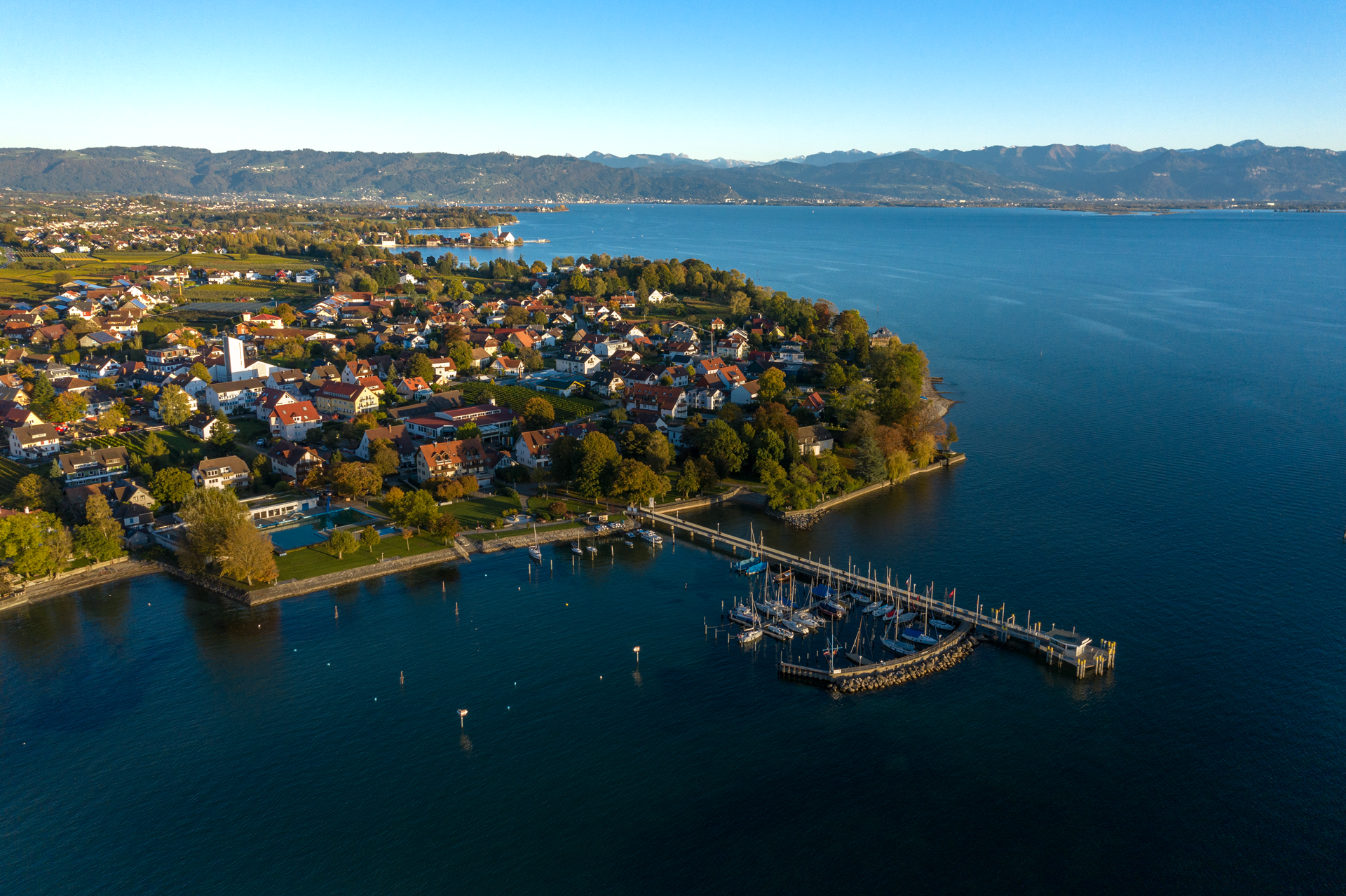Luftaufnahme mit Blick vom See her auf den Landesteg und den Ort