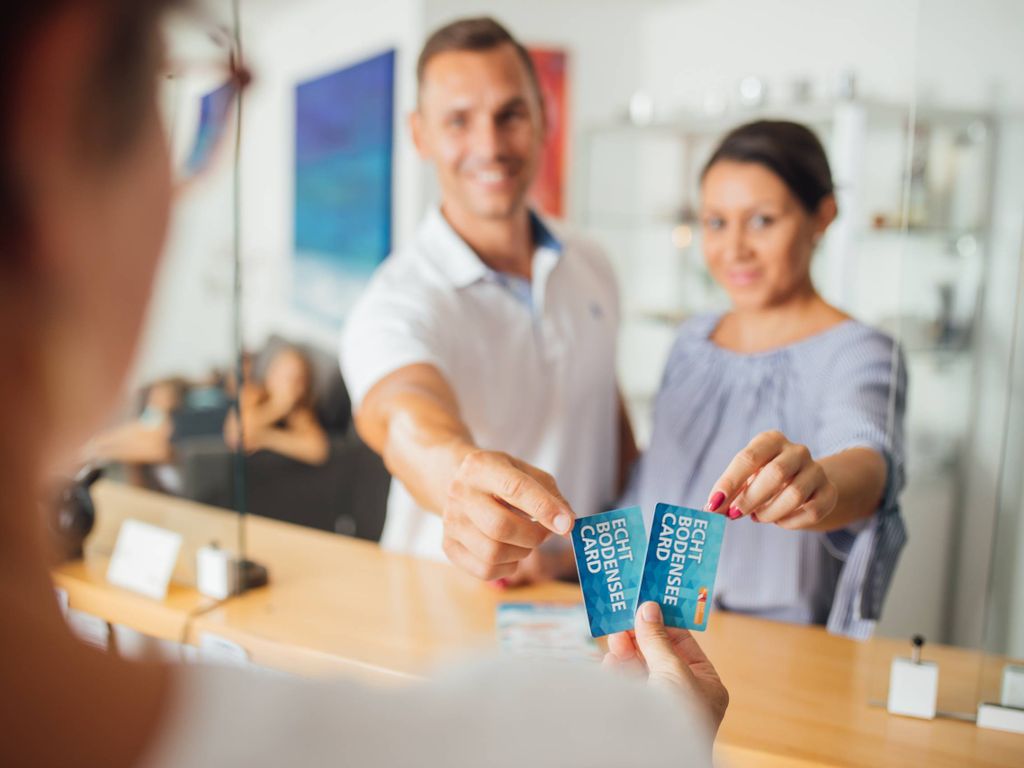 Mann und Frau zeigen an einem Counter ihre Echt Bodensee Card