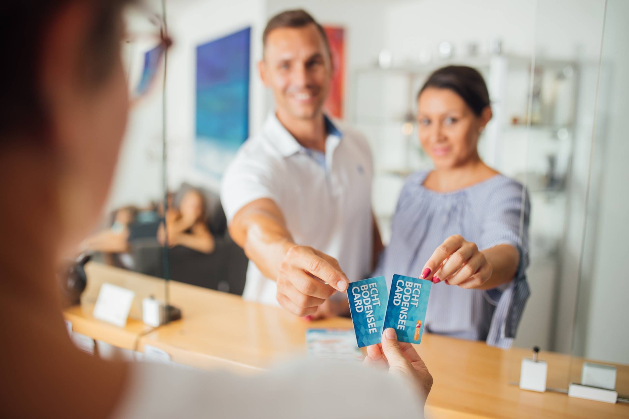 Mann und Frau zeigen an einem Counter ihre Echt Bodensee Card