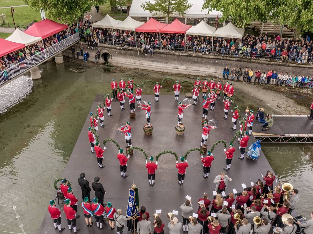 Schäfflertanz aus der Vogelperspektive, Man sieht den Musikverein, die Schäffler mit den Kränzen und die Reifenschwinger in Aktion, ebenso die Zuschauer