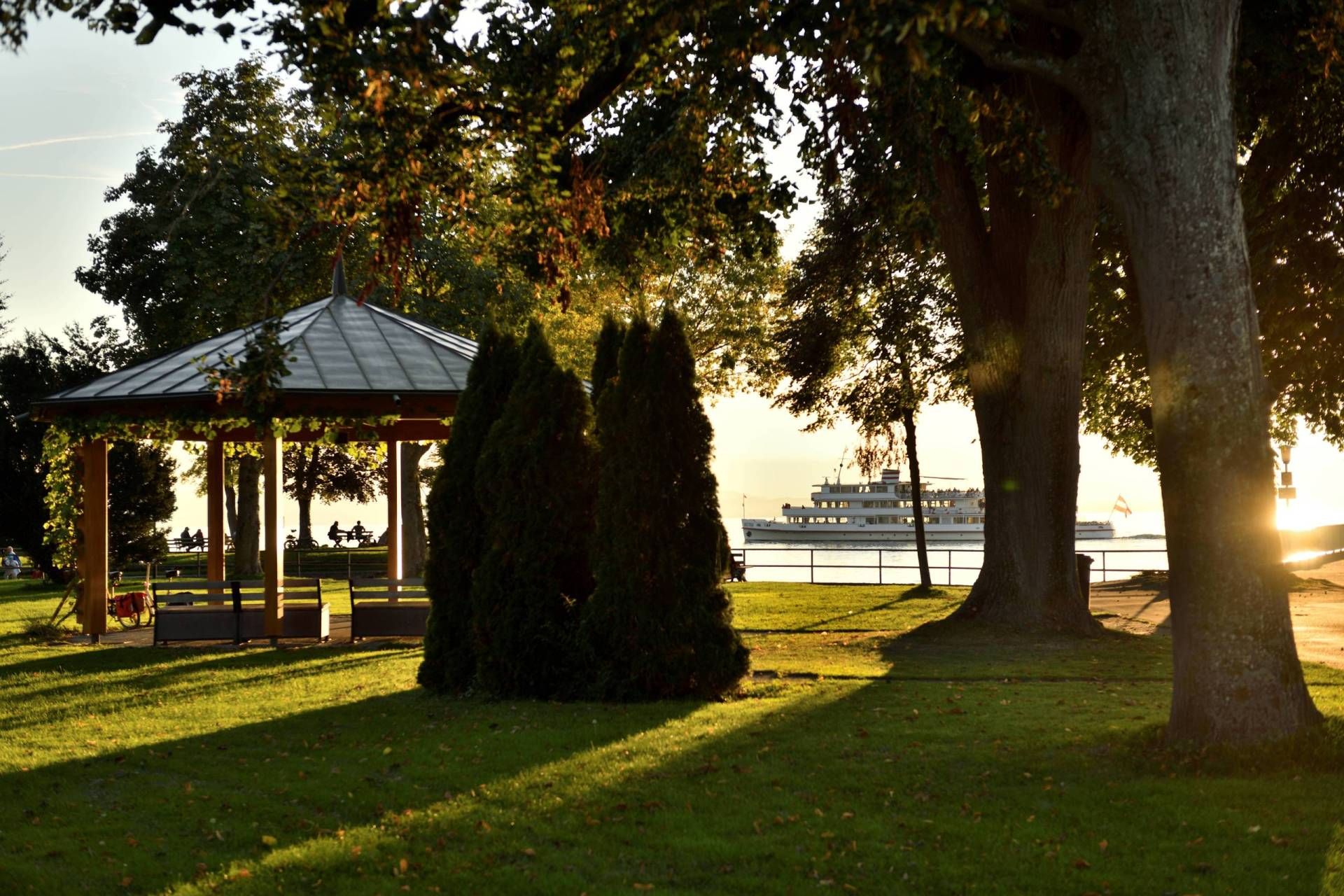 Uferpark mit Pavillon und Schiff im Hintergrund, Abendstimmung