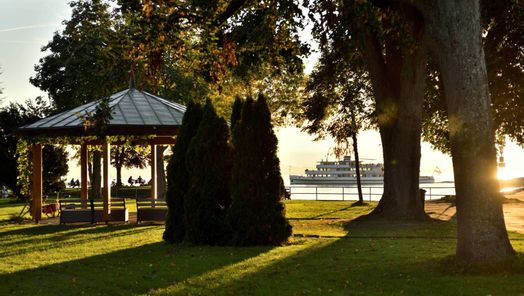 Uferpark mit Pavillon und Schiff im Hintergrund, Abendstimmung