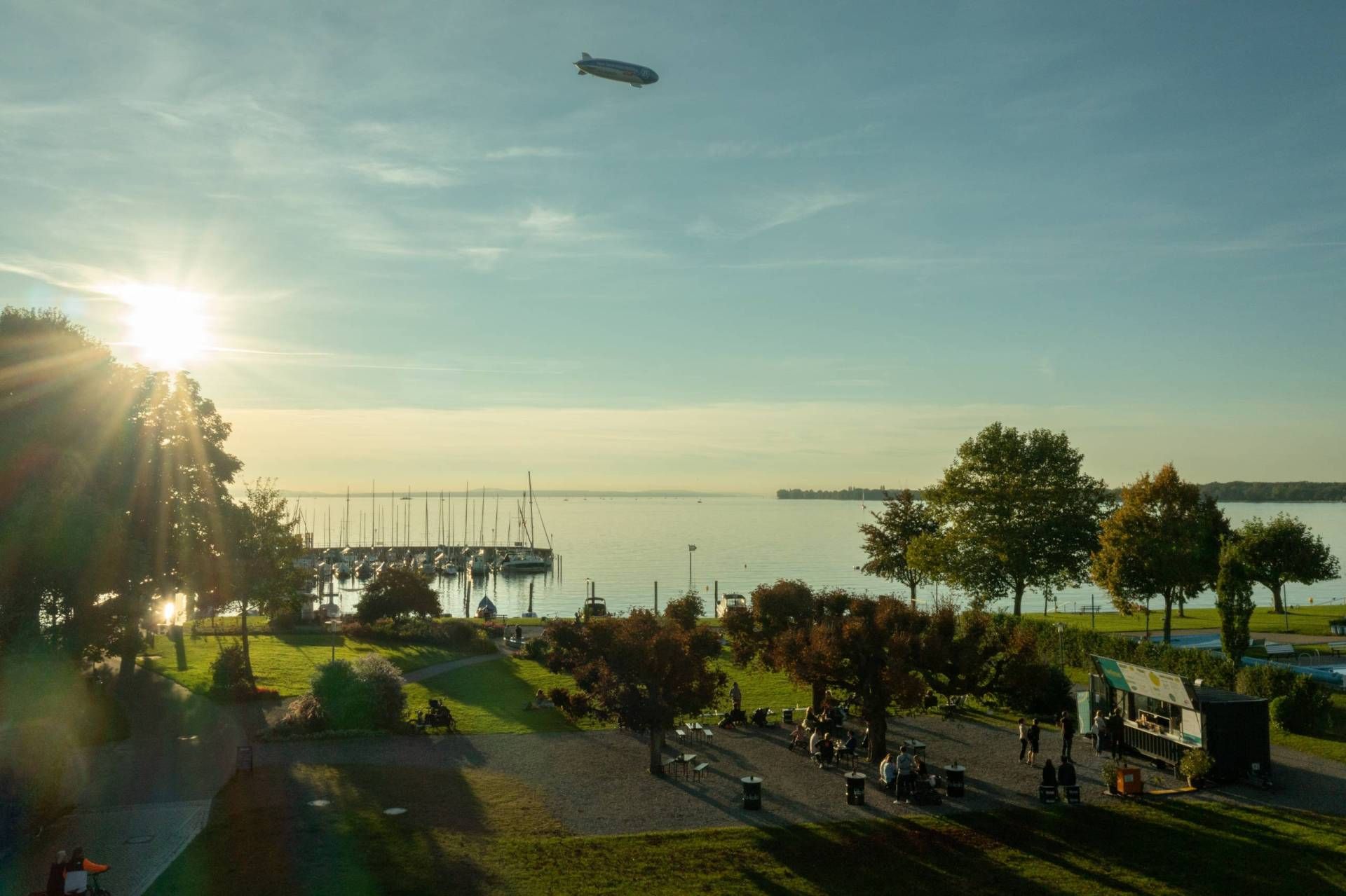Blick von oben auf den Hafen, den See, den Uferpark mit Foodtruck